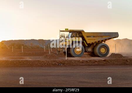 Déchargez le camion sur la voie de transport au coucher du soleil dans la zone d'extraction à ciel ouvert. Banque D'Images