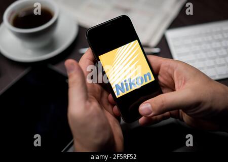 New York, New York / Etats-Unis - 11 11 2019: Logo de Nikon sur l'iPhone X dans les mains au bureau Banque D'Images