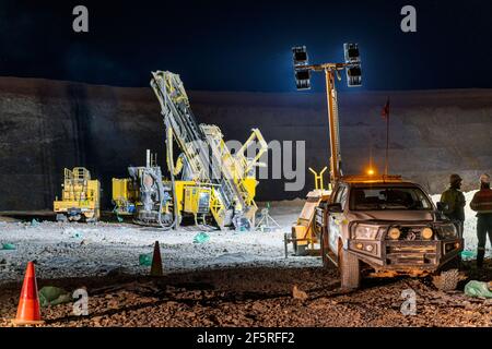 Forage de forage en exploitation dans une mine à ciel ouvert la nuit en dessous projecteurs Banque D'Images