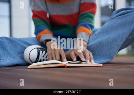 Étudiant à l'université, apprentissage de la langue, préparation à l'examen, concentration sur les doigts. Concept d'éducation. Femme lisant un livre à l'extérieur Banque D'Images