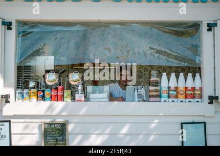 Umea, Suède le 9 juin 2020 : un jeune garçon au guichet de glace ouvert avec des boissons gazeuses alignées et des garnitures de sauce à la crème glacée attend les clients. Su Banque D'Images