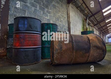 Fûts ou fûts d'huile anciens de Rusty isolés dans une usine Banque D'Images