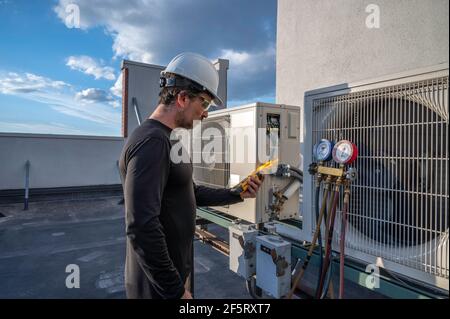 Un technicien HVAC professionnel prend l'ampérage sur un système de climatisation à mini-dépairage sans raccordement. Banque D'Images