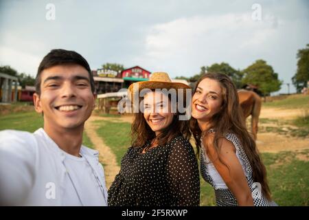 Trois amis utilisant Smart Phone pour la photographie avec les chevaux dans le Ranch. Jour d'été Banque D'Images