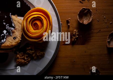 Gâteau aux noix avec zeste d'orange de sauce au chocolat sur l'assiette en faible lumière. Banque D'Images