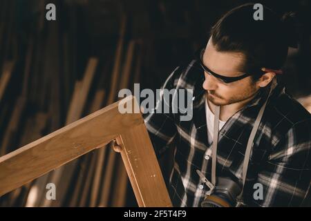 Menuisier homme professionnel qualifié dans le travail de bois regardant le détail de chef-d'œuvre woodcraft dans atelier de meubles Banque D'Images