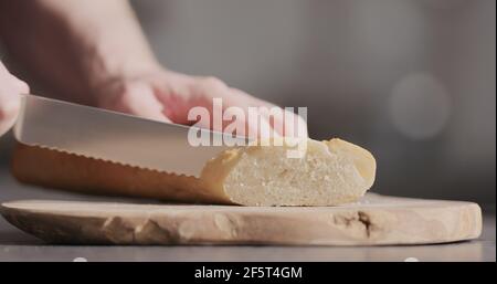 homme à trancher à la main la baguette sur une planche en bois d'olive, photo large Banque D'Images