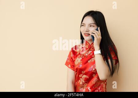 Jeune fille chinoise téléphone appelant avec un ami dressing Qipao traditionnel tissu. Banque D'Images