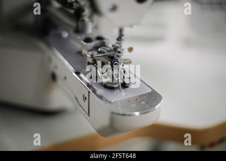 Image de faible profondeur de champ (mise au point sélective) avec une machine à coudre électrique dans une usine de textile. Banque D'Images