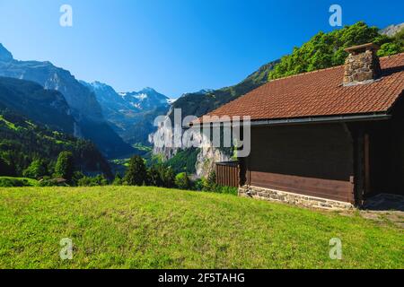Jolie maison en bois sur le terrain vert alpin et vue fantastique avec la vallée de Lauterbrunnen depuis la colline, Oberland bernois, Suisse, Europe Banque D'Images