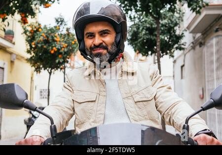 De dessous de la violente ethnie motard masculin dans la conduite de casque moto contemporaine avec vue sur la ville Banque D'Images
