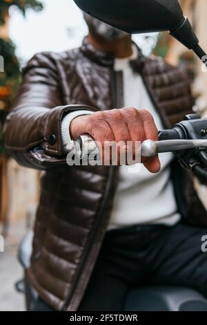 De dessous court motard masculin non reconnaissable conduisant une moto contemporaine pendant vue sur la ville Banque D'Images