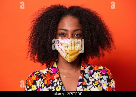 Serveur positif en uniforme et masque plaçant des tasses de café filtre aromatique sur le plateau au comptoir avec le clavier de la station d'accueil dans le restaurant pendant le coronavir Banque D'Images