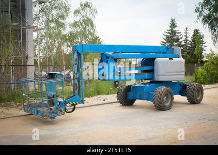 Plate-forme de travail bleue sur fond de bâtiment. Grue mobile sur le chantier. Levage de la rampe à l'extérieur. Ascenseur télescopique à louer Banque D'Images