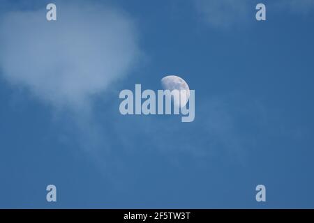Premier quart de lune dans le ciel nuageux du soir Banque D'Images