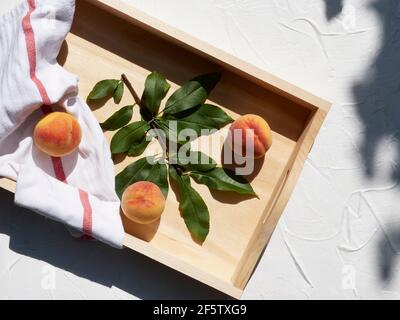 Pêches biologiques fraîchement cueillies sur un plateau en été soleil avec feuilles Banque D'Images