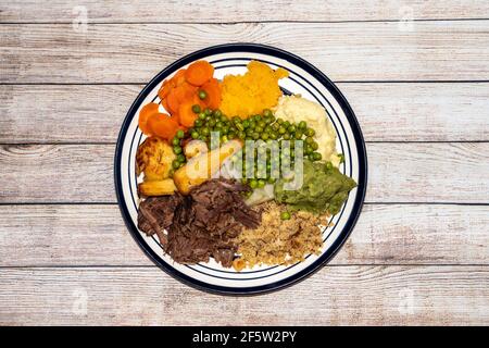 Dîner du dimanche de bœuf haché râpé lentement cuit sur une assiette avec beaucoup de légumes tels que les petits pois, les petits pois, les panais, les pommes de terre rôties et les carottes, Banque D'Images