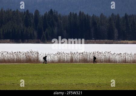 28 Mars 2021, Bavière, Füssen: Promenades le long de la rive de l'Hopfensee au soleil. Photo : Karl-Josef Hildenbrand/dpa Banque D'Images