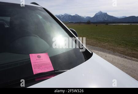 28 mars 2021, Bavière, Füssen: Un avis d'infraction administrative est collé à l'essuie-glace d'une voiture garée dans une zone de conservation du paysage. De nombreuses excursions ont été attirées au Hopfensee au soleil. Beaucoup d'entre eux sont venus en voiture. Photo : Karl-Josef Hildenbrand/dpa Banque D'Images