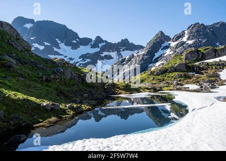 Les montagnes se reflètent dans le lac Isvatnet avec de la glace, des montagnes et de la neige, au Trollfjord Hytta, au Trollfjord, Lofoten, Nordland, Norvège Banque D'Images