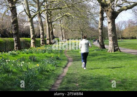 Femme qui fait du jogging sous le soleil du printemps à Regents Park, dans le nord de Londres, au Royaume-Uni Banque D'Images