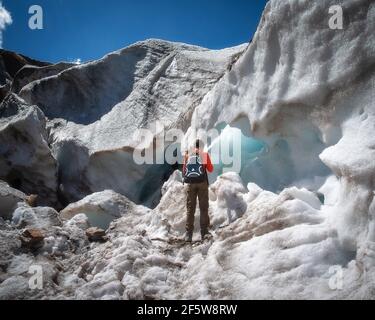 un adolescent avec un sac à dos se tient près de la neige Mur du glacier Alibeksky à Dombay Banque D'Images