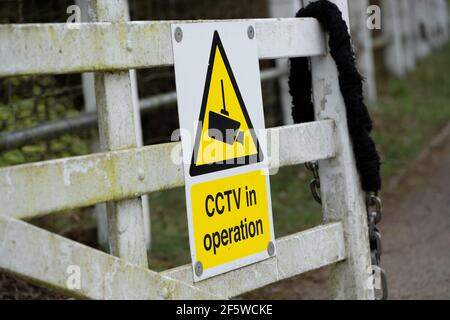 Panneau d'avertissement CCTV générique fixé à une porte de jardin dans un endroit rural. Le signe aide à dissuader les criminels potentiels qu'ils sont enregistrés. Banque D'Images