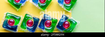 capsules pour le lavage avec du gel vert et jaune sur un espace de copie en arrière-plan blanc Banque D'Images