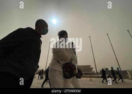 Pékin, Chine. 28 mars 2021. Les gens portent des masques pour visiter le site pittoresque de Tiananmen à Pékin, entouré de tempêtes de sable. Le soleil est bleu en raison des tempêtes de poussière.UNE épaisse brume descend sur Beijing comme une tempête de sable couvre la ville. L'observatoire national de la Chine a émis une alerte jaune pour les tempêtes de sable dans la partie nord du pays. (Photo de Sheldon Cooper/SOPA Images/Sipa USA) crédit: SIPA USA/Alay Live News Banque D'Images
