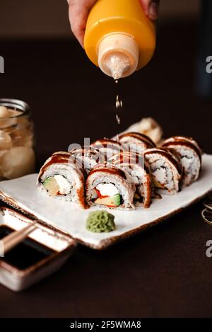 Sushi à l'anguille, arrosé de sauce soja et parsemé de graines de sésame Banque D'Images