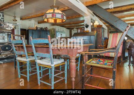 Table à manger en bois de pin teinté brun antique avec peint en vieilli chaises de siège en bois bleu rasé dans la salle à manger avec large parquet en pin Banque D'Images