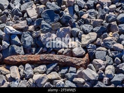 Pointe de chemin de fer rouillée et recouverte de roches de gravier Banque D'Images