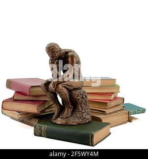 La statue de Thinking Man devant de vieux livres vintage avec blanc arrière-plan Banque D'Images