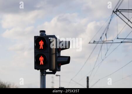 Vue à angle bas, feu de circulation avec symbole humain rouge pour arrêter les personnes à pied à la traversée contre le ciel bleu. Banque D'Images