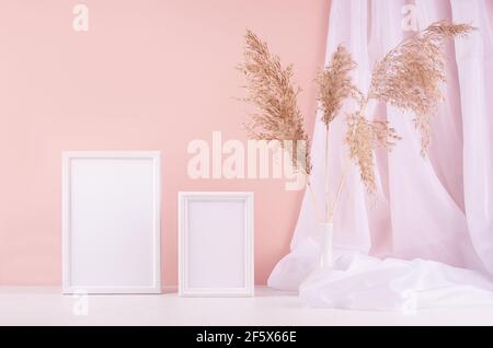 Décoration calme avec ensemble de deux cadres photo vierges pour le texte, le design, l'affiche, le rideau de soie, les roseaux moelleux sur la table en bois blanc, le mur rose. Modèle pour di Banque D'Images