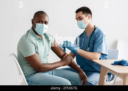 Infirmière en masque médical et gants tenant la seringue et donnant à la grippe du patient, injection de covid-19 dans le bras Banque D'Images