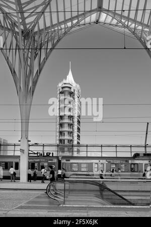 Le train arrive à la gare. Les gens attendent le train. Nous pouvons voir la vue sur la ville et une partie de la structure architecturale. Noir et blanc Banque D'Images