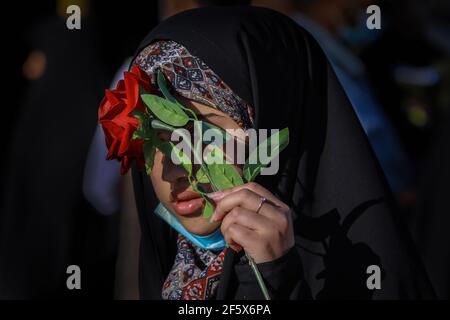 Karbala, Irak. 28 mars 2021. Une femme couvre son visage avec une rose artificielle pendant les célébrations du Nisf de Shaban (Mid-Sha'ban). Chaque année, mi-Sha'ban est observé par les communautés musulmanes la nuit entre le 14 et le 15 de Sha'aban, qui est le huitième mois du calendrier islamique. Credit: Ameer Al Mohmedaw/dpa/Alamy Live News Banque D'Images