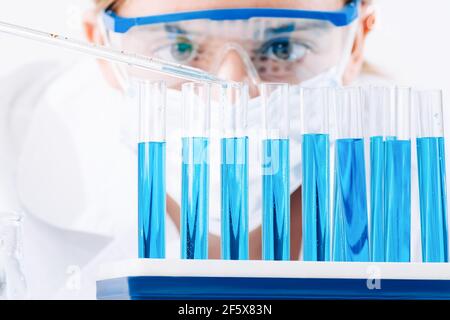 Gros plan d'une chercheuse utilisant une micropipette pour remplir des tubes à essai.l'assistant de laboratoire dans un laboratoire avec des tubes à essai produit des échantillons de vaccins. Banque D'Images