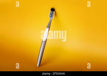 Brosse à dents en plastique gris sur fond jaune. Concept dentaire et de soins de santé, équipement pour l'hygiène bucco-dentaire personnelle. Banque D'Images