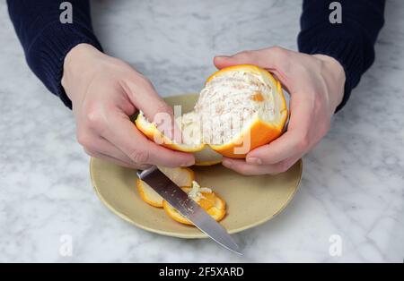 Les mains de l'homme s'écaillent une orange. Concept d'alimentation saine Banque D'Images