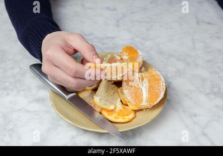 Les mains de l'homme s'écaillent une orange. Concept d'alimentation saine Banque D'Images