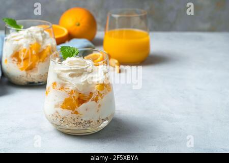 Dessert orange avec crème et menthe sur fond gris. Crème fouettée et fruits. Dessert concept. Banque D'Images