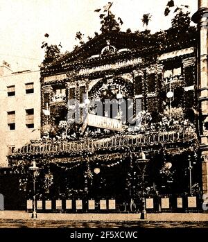 Été 1902. Londres décore les rues pour la célébration du couronnement d'Edward VII et de son épouse Alexandra du Danemark. Initialement prévue pour le 26 juin de cette année-là, la cérémonie avait été reportée à très court préavis, parce que le Roi avait été pris malade et a dû être hospitalisé. Cette ancienne photo montre l'ancien Empire Theatre. Banque D'Images