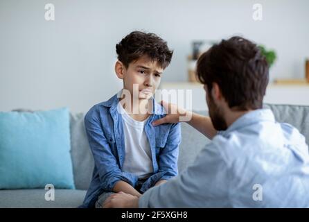 Père et fils triste ayant du cœur à cœur parler à la maison, papa essayant de résoudre des problèmes, parent apaisant garçon Banque D'Images