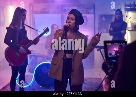 Chanteuse chantant dans le microphone et se présentant avec elle groupe et enregistrement de leur concert sur la vidéo Banque D'Images