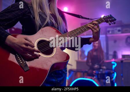 Gros plan d'une femme jouant de la guitare pendant sa performance sur le concert Banque D'Images