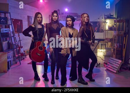 Portrait du groupe musical féminin moderne regardant l'appareil photo pendant ils se sont spectacle à la discothèque Banque D'Images