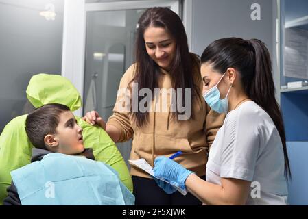 Le dentiste et la mère de l'enfant signent un accord de document avant le dentiste traitement Banque D'Images