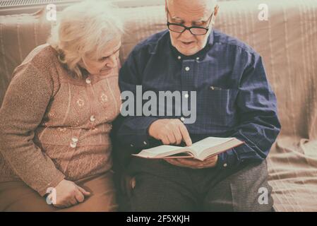 Couple de personnes âgées lisant la bible et priez ensemble à la maison. Banque D'Images